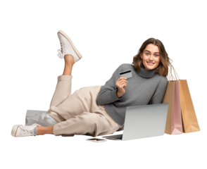  a woman lying on the floor with a laptop, holding a credit card in one hand and shopping bags near her leg, with a smiling face, on a transparent background, in png format.
