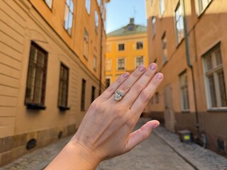 Romantic landscape image of an oval diamond engagement ring or wedding band held high in charming...