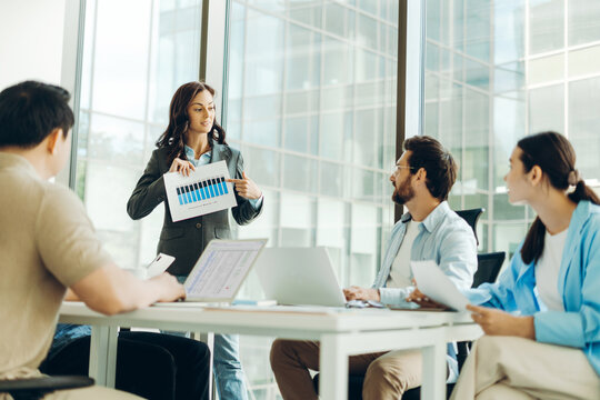 Businesswoman showing chart to colleagues during presentation in office meeting room