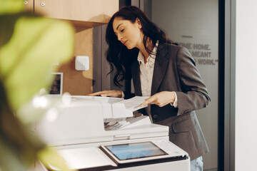 Businesswoman making copies in office using printer machine