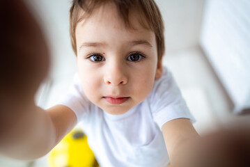 Child reaching out, curious. A young child stretches out their hand towards the camera, displaying...