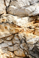 Natural stone surface with rugged textures, cracks, and earthy tones, highlighting the raw beauty of geological formations. Perfect for backgrounds and nature-inspired design concepts.