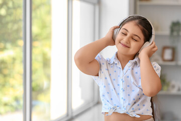 Little girl in headphones listening to music at home
