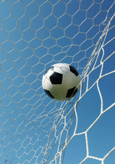 soccer ball hitting the net against blue sky