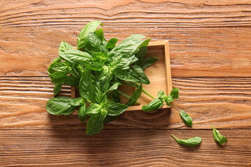 Box with fresh green basil leaves on wooden background