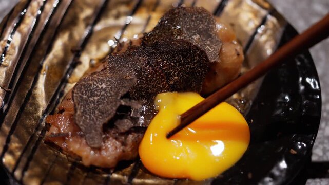 Close-up of luxurious A5 Wagyu beef paired with shaved black truffle and a raw egg yolk, a rich and indulgent combination. Perfect for gourmet food videos, high-end restaurant. High quality 4k footage