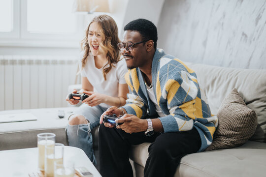 A cheerful couple shares laughter and joy while playing video games together, fostering connection and fun in a relaxed home environment.