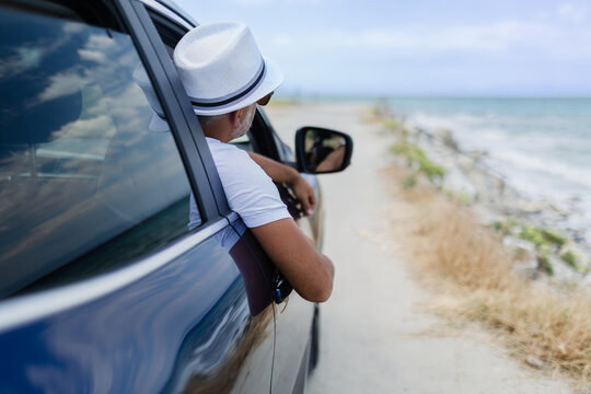 Man enjoying a coastal drive with a scenic view while relaxing in a car on a sunny day