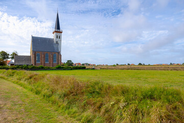 Typical landscape of Texel island with small village and picturesque church (Hervormde kerk) under blue sky and white clouds, A little town on the wadden islands, Den Hoorn, Noord Holland, Netherlands