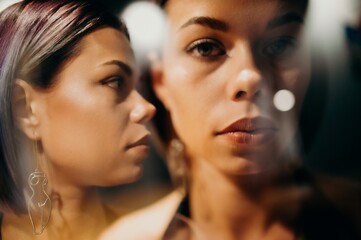 Artistic portrait of a young woman captured through reflection, showing two overlapping views of...