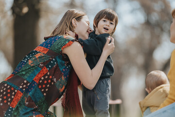 Warm scene of a mother holding her smiling child outside, creating a heartwarming moment of family bonding. The natural afternoon setting reflects a relaxed and cherishing environment.