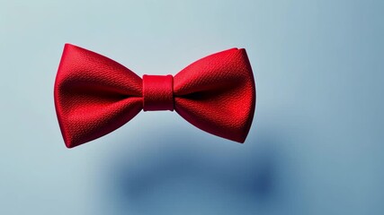 A red bow tie is placed neatly against a light blue background, showcasing timeless fashion and style