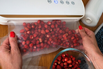 Vacuum sealer of strawberries, honeysuckle in bag, packaging for long-term storage . Vacuum packing...