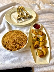 Fried rice with spring rolls and sauce served on white background
