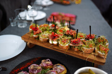 Sandwiches with cheese, ham, tomatoes and herbs on a wooden tray.