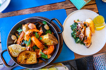 buzara traditional seafood dish in Croatia with shrimp mussels and red sauce and grilled calamari squid