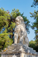 Obraz premium Ancient Lion of Amphipolis statue in Greece under clear blue sky surrounded by pine trees