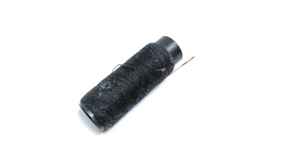 Coil of black thread. The needle is inserted into the spool of thread