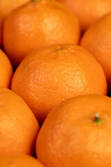 Unpeeled orange tangerines stacked together, a large number of ripe orange tangerines