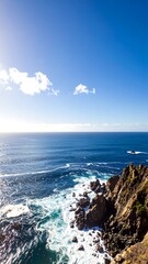 Ocean waves crashing against rocky cliffs under a clear sky