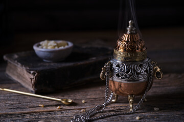 Incense burner with frankincense resin on wooden table – moody style
