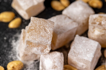 Turkish delight cubes and toasted peanuts on a black slate surface, closeup