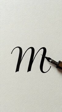 Handwriting letter 'M' with calligraphy pen on white paper  