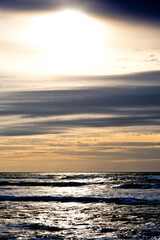 Obraz premium Waves crashing on the shore under a cloudy sky.