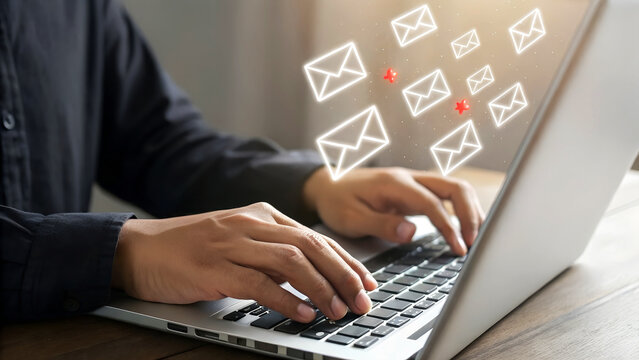 Man actively typing on a laptop as email icons float upwards, signifying digital communication and online messaging.