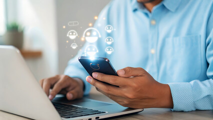 Man engaging with glowing digital feedback icons on smartphone while working on laptop, representing online communication and customer satisfaction.