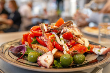 Traditional Neapolitan seafood salad with octopus, tomatoes, olives, onions, and herbs served fresh in Mediterranean restaurant in Naples, Italy, caponata