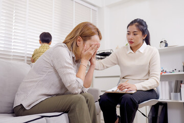 Psychological therapy session with asian female therapist comforting emotional single mother while...