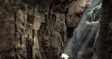 Sunlight streams through a rocky cavern, illuminating the rugged textures and formations. Shadows dance on the walls, creating a serene and magical atmosphere within the cave.