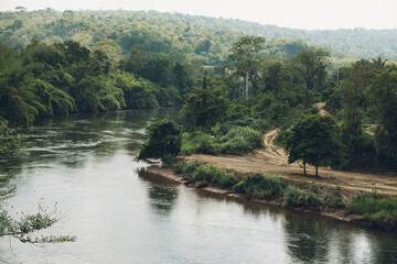 River Kwai flowing through dense vegetation and rainforest trees in Kanchanaburi, Thailand