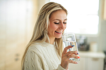 Woman Drinking Water and smiling at home