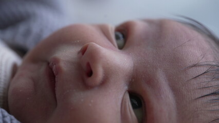 Fototapeta premium Newborn's face in close-up with eyes wide open, curiosity and innocence of early life, emphasizing the delicate skin and fine details of the baby's facial features