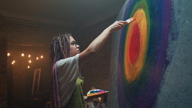 A Creative Artist Skillfully Painting a Beautiful and Vibrant Rainbow Mural Composition