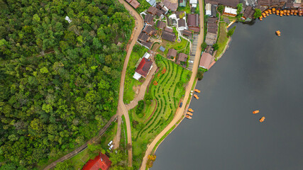 aerial top view of a lakeside village, showcasing a mix of rustic architecture, lush greenery, and...