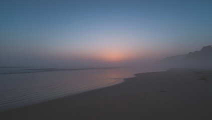 Misty Beach Sunrise with Fog Rolling Onto the Shoreline View