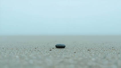 Single Stone on Sandy Beach with Foggy Background in Minimalist Style