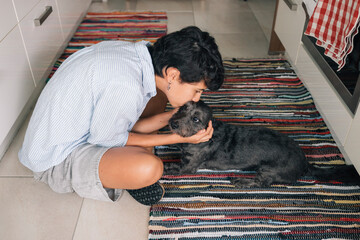 Young girl kissing her adorable dog in the kitchen