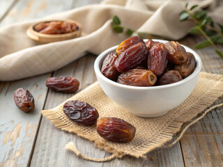 White ceramic bowl filled with dried dates on wooden table