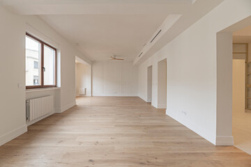 Industrial-chic empty living room with exposed pipes in the ceiling, smoothed cement floors, and factory-style windows