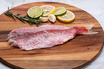 raw snapper fcut in half on wooden table