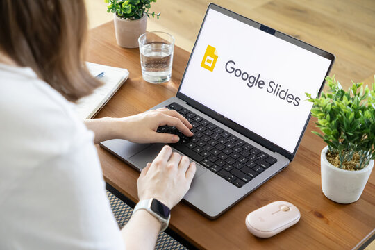 Poznan, Poland - August 23, 2025: Google Slides application visible on laptop screen as person types, creating presentation content for remote work and digital office use