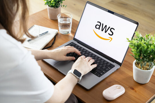 Poznan, Poland - August 23, 2025: AWS logo prominently displayed on a laptop screen while a person types, symbolizing cloud computing and modern digital work