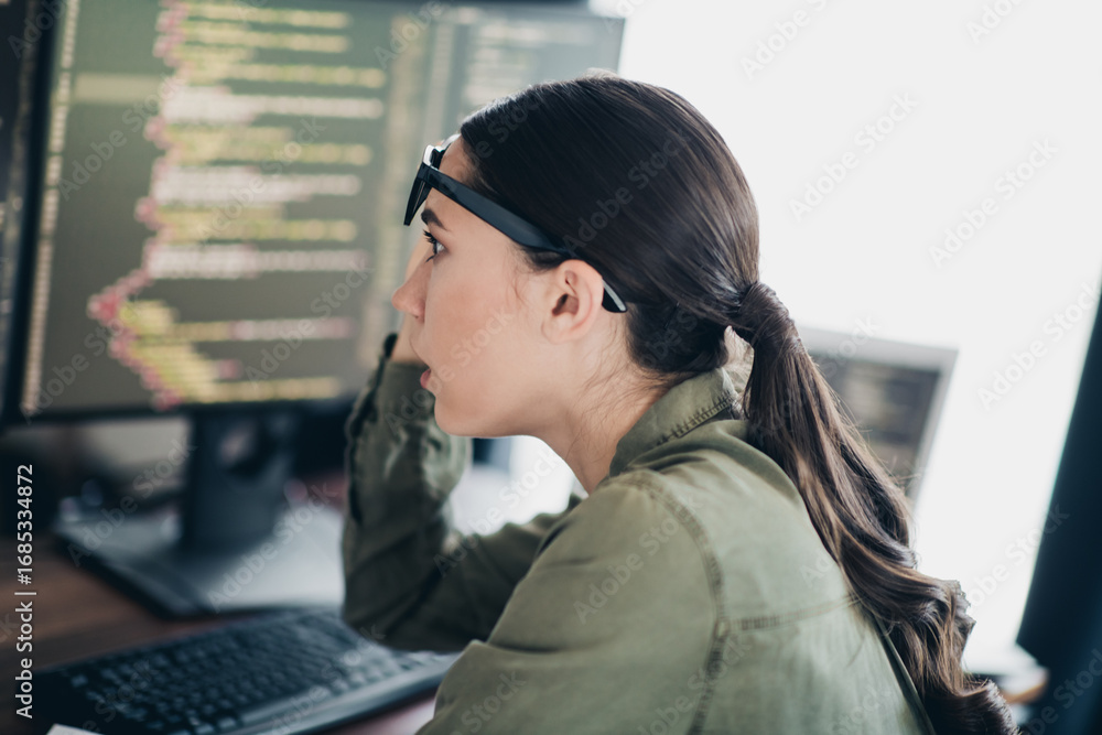 Poster young woman working on computer programming while focusing on task wearing casual clothing in a mode