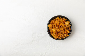 Crispy fried onions in a bowl on a wooden table. Roasted Onions. Seasoning for dishes. Spices....