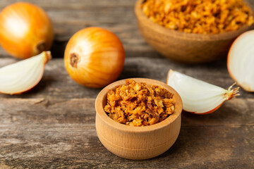 Crispy fried onions in a bowl on a wooden table. Roasted Onions. Seasoning for dishes. Spices. Salad dressing. Space for text. Copy space