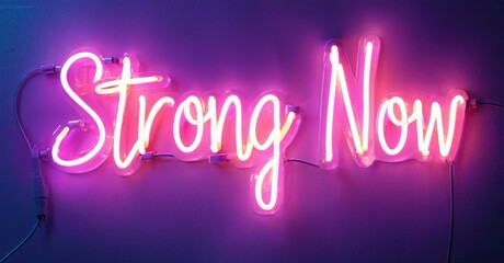 Bright pink neon sign displays words Strong Now against purple wall. Simple message, modern aesthetic, vibrant illumination.